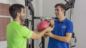 Entrenador de Time2Train con buen ambinte pasa pesa kettel a un deportista